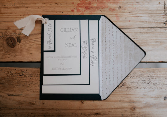 Black and white wedding invitation against wooden background